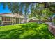 Expansive backyard featuring artificial turf, mature trees, and a covered patio area, perfect for outdoor activities at 10213 Treasure Mountain Ct, Las Vegas, NV 89129