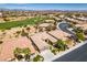 Expansive aerial view of a desert neighborhood near a golf course and city skyline under a bright blue sky at 10372 Premia Pl, Las Vegas, NV 89135