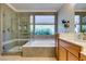 Well-lit bathroom with glass shower, tub, and wood cabinets for a spa-like experience at 10372 Premia Pl, Las Vegas, NV 89135