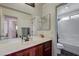 Bright bathroom featuring a cherry vanity with double sinks and a tub with shower at 10519 Bella Camrosa Dr, Las Vegas, NV 89141