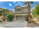 Charming two-story home featuring desert landscaping, a two-car garage, and mature palm trees at 10519 Bella Camrosa Dr, Las Vegas, NV 89141