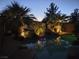Ambient backyard pool with tropical landscaping, serene rock waterfall, and soft evening lighting at 10519 Bella Camrosa Dr, Las Vegas, NV 89141