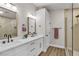 Contemporary bathroom featuring double sinks with white countertops, wood-look floors, and a glass shower at 10886 Porto Foxi St, Las Vegas, NV 89141