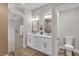 Bright bathroom featuring double sinks with white cabinets, wood-look floors, and glass shower at 10886 Porto Foxi St, Las Vegas, NV 89141