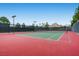Well-maintained tennis court with green and red surface, surrounded by trees and fencing at 1113 Via Della Costrella, Henderson, NV 89011