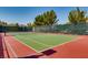 Well-maintained tennis court with green and red surface, surrounded by trees and fencing at 1113 Via Della Costrella, Henderson, NV 89011