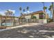 View of community pool and residential building with tropical landscaping and an iron fence on a bright day at 1420 Vegas Valley Dr # 22, Las Vegas, NV 89169