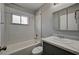 Cozy bathroom with white tiled shower-tub, gray vanity, and large, mirrored cabinet at 155 Magnesium St, Henderson, NV 89015