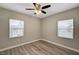 Bedroom with a ceiling fan, wood-look floors, neutral paint, and two windows at 155 Magnesium St, Henderson, NV 89015