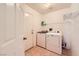 Well-lit laundry room featuring side-by-side washer and dryer, storage shelves, and access door at 2105 Poppywood Ave, Henderson, NV 89012