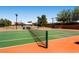 Well-maintained tennis court with green and orange surface, complete with net and lighting for evening play at 2105 Poppywood Ave, Henderson, NV 89012