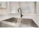 Close-up of a stainless steel farmhouse sink with a black faucet and marble countertops by a window at 2520 Springridge Dr, Las Vegas, NV 89134