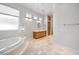 Bright bathroom featuring a soaking tub, wood vanity, and multiple windows for natural light at 2742 Darby Falls Dr, Las Vegas, NV 89134