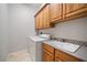 Well-equipped laundry room offers a washer, dryer, sink, and wood cabinets for convenience at 2742 Darby Falls Dr, Las Vegas, NV 89134