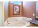 Bathroom featuring a soaking tub with tile surround, framed picture, and blue tinted arched window above at 2809 Mountain Violet Ct, Las Vegas, NV 89108