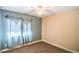 Cozy bedroom with neutral carpet, two-tone paint, a ceiling fan, and large window covered with decorative curtains at 2809 Mountain Violet Ct, Las Vegas, NV 89108