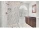 Modern bathroom features a marble tile surround glass shower, dark wood vanity and half moon window at 2873 Cambretto Dr, Henderson, NV 89074