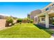 Backyard features artificial turf, a covered patio, and mature trees providing privacy at 3042 Echoed Rondel Ln, Henderson, NV 89044
