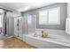 Modern bathroom with a glass-enclosed shower, soaking tub, and plantation shutters at 3042 Echoed Rondel Ln, Henderson, NV 89044