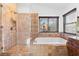 Ensuite bath featuring a glass enclosed shower, soaking tub, tile surround, and large window at 356 Clark Dr, Henderson, NV 89074