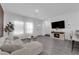 Modern living room with gray laminate floors, ample light, and a sleek entertainment center at 471 Secret Cove Ct, Henderson, NV 89002