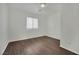 A simple bedroom with a window, light fixture, and wood-look flooring at 6525 Bismark Hills St, North Las Vegas, NV 89084