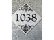 Close up of the house number 1038 on a decorative plaque mounted to a textured wall at 6955 N Durango Dr # 1038, Las Vegas, NV 89149
