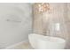 Freestanding tub under a chandelier next to the onyx shower in this modern bathroom at 7185 Ranchito Cir, Las Vegas, NV 89120