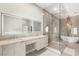 Bright bathroom featuring double sinks, a light up mirror, glass shower, and tub with a chandelier at 7185 Ranchito Cir, Las Vegas, NV 89120