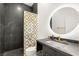 Modern bathroom with black and white tile, sleek vanity, and circular mirror at 7185 Ranchito Cir, Las Vegas, NV 89120