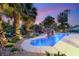 Luxurious backyard swimming pool with a rock waterfall feature, surrounded by tropical landscaping at 7185 Ranchito Cir, Las Vegas, NV 89120