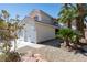 Two-story home showcasing a three-car garage and lush desert landscaping at 7825 Desert Bell Ave, Las Vegas, NV 89128