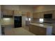 Spacious kitchen featuring tile counters, a kitchen island, ample cabinet space, and modern black appliances at 8052 Marbella Cir, Las Vegas, NV 89128