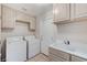 Well-lit laundry room with washer, dryer, sink and cabinets at 8052 Marbella Cir, Las Vegas, NV 89128