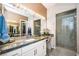 A modern bathroom with granite countertops, a large mirror, and a glass-enclosed shower at 9858 Gemstone Sunset Ave, Las Vegas, NV 89148