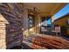 Cozy front porch with brick flooring, adorned with outdoor seating and a decorative stone wall at 9858 Gemstone Sunset Ave, Las Vegas, NV 89148