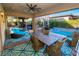 An outdoor covered patio with a dining area, lounge chair and a view of the pool at 9858 Gemstone Sunset Ave, Las Vegas, NV 89148