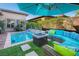 A beautiful outdoor pool area with lounge seating, an umbrella, and a fire pit at 9858 Gemstone Sunset Ave, Las Vegas, NV 89148