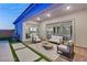 Comfortable covered patio with outdoor seating, brick flooring, and sliding glass doors to the home's interior at 10086 Mountain Foothills Ave, Las Vegas, NV 89149