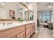 Bright main bathroom with double vanity, large mirrors, and access to bedroom with bay window at 10309 Broom Hill Dr, Las Vegas, NV 89134