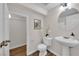 Clean bathroom features a pedestal sink, toilet, and closet, complemented by a round mirror and wood floors at 11164 African Sunset St, Henderson, NV 89052