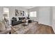 Beautiful living room with gray sofa, light wood floors, staircase and large windows offering natural light at 11164 African Sunset St, Henderson, NV 89052