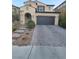 Two-story home with a two-car garage, stone driveway, desert landscaping, and a covered front entry at 11815 Corenzio Ave, Las Vegas, NV 89138