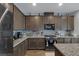 Modern kitchen featuring dark cabinets, stainless steel appliances, granite countertops, and decorative backsplash at 1401 Cattail Falls St, Boulder City, NV 89005