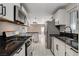 Open-concept kitchen with stainless steel appliances, black countertops and white cabinetry with access to the living room at 1708 Poplar Ave, Las Vegas, NV 89101