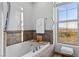 Bathroom featuring a soaking tub with tile surround and scenic window view at 20 Via Visione # 104, Henderson, NV 89011
