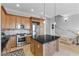 Traditional kitchen with stainless appliances, island with granite counters and tile backsplash, and stairway at 20 Via Visione # 104, Henderson, NV 89011