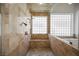 Walk-in shower with dual shower heads and a bench, encased in marble with natural light at 2805 High Sail Ct, Las Vegas, NV 89117