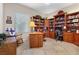Spacious home office with wooden built-in bookcases, a large desk, and bright natural light at 2864 Sumter Valley Cir, Henderson, NV 89052