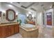 Bathroom featuring a soaking tub, dual sinks with granite countertops, and natural lighting at 3051 Traverse Creek Ln, Las Vegas, NV 89135